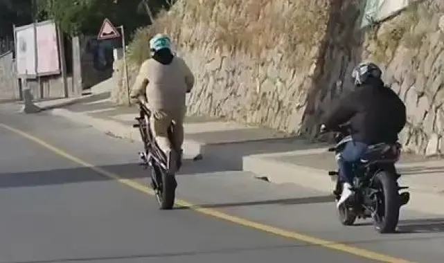 Akrobasi hareketleri yaparak motosiklet kullanan şahıs kamerada