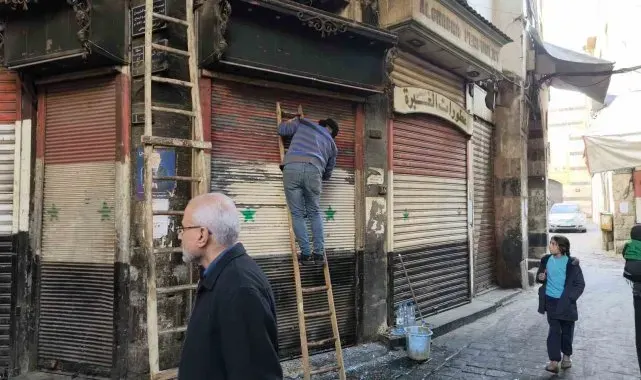 Esnaflar kepenklerindeki eski Suriye bayraklarını kazımaya başladı